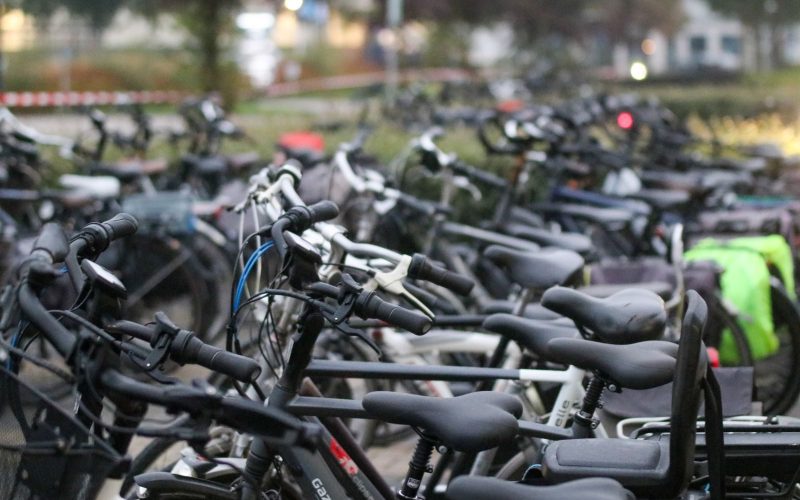 A crowded bicycle parking area outdoors with various bikes parked in rows.